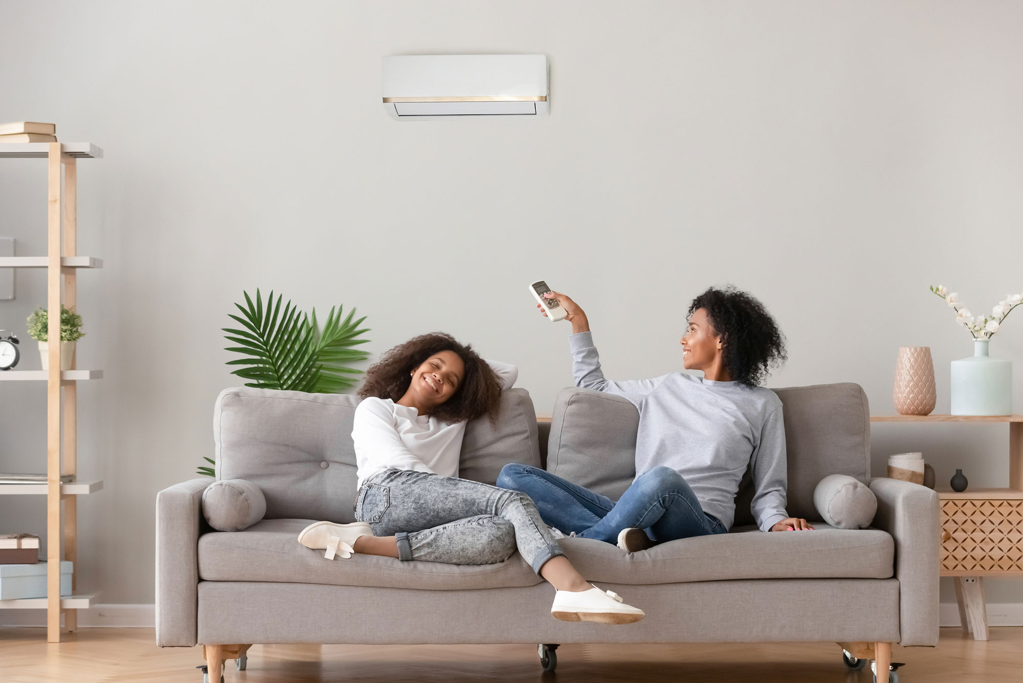 women on couch with mini split heat pump remote control